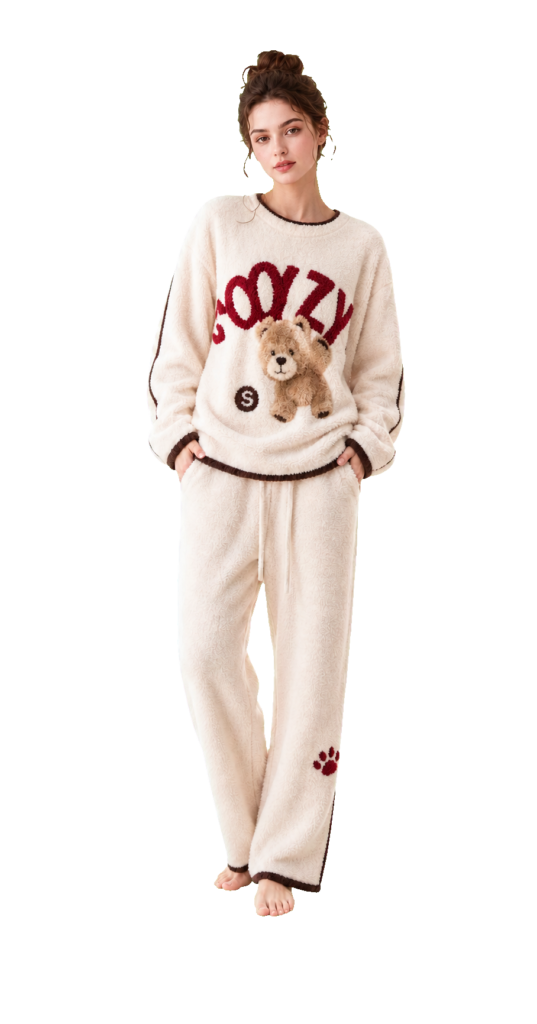 Model wearing a cream fleece pajama set with a teddy bear motif and brown trim.
