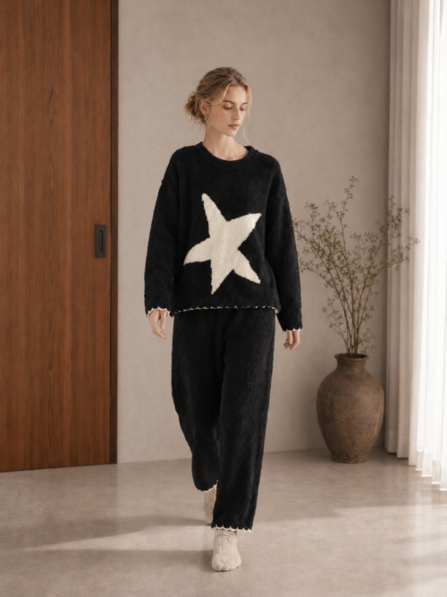 Woman wearing a black half fleece pajama set with a cream star and scalloped trim, full-body front view