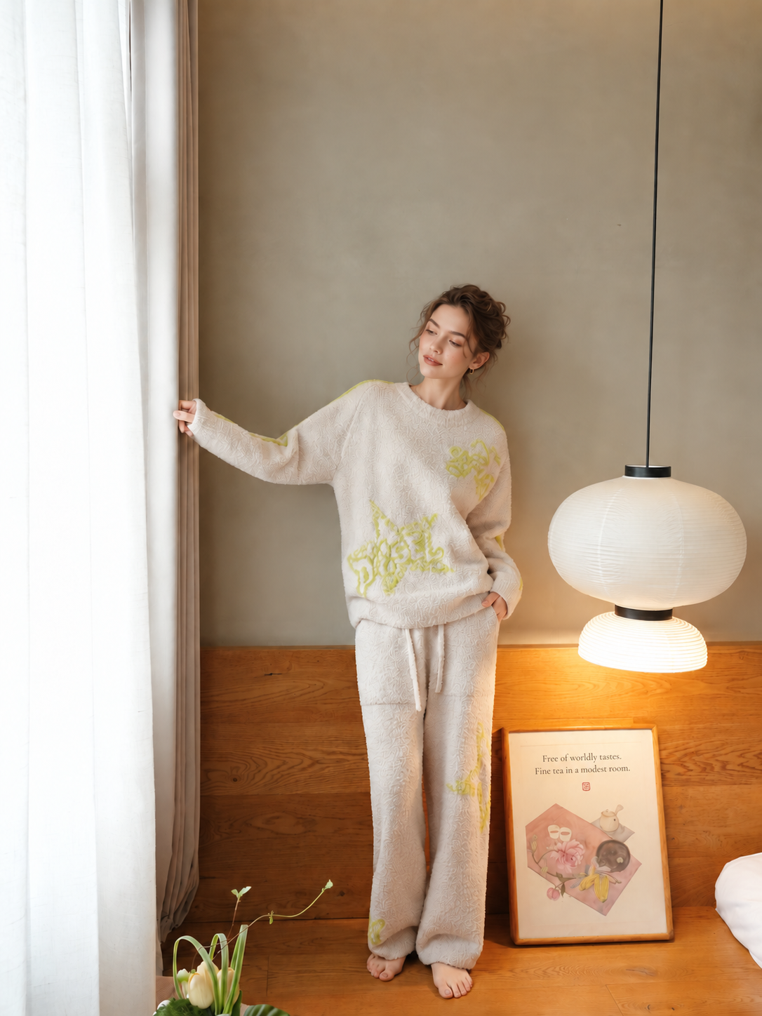 Full-body view of a woman wearing beige half fleece pajamas with lime star lettering and contrast sleeve stripes