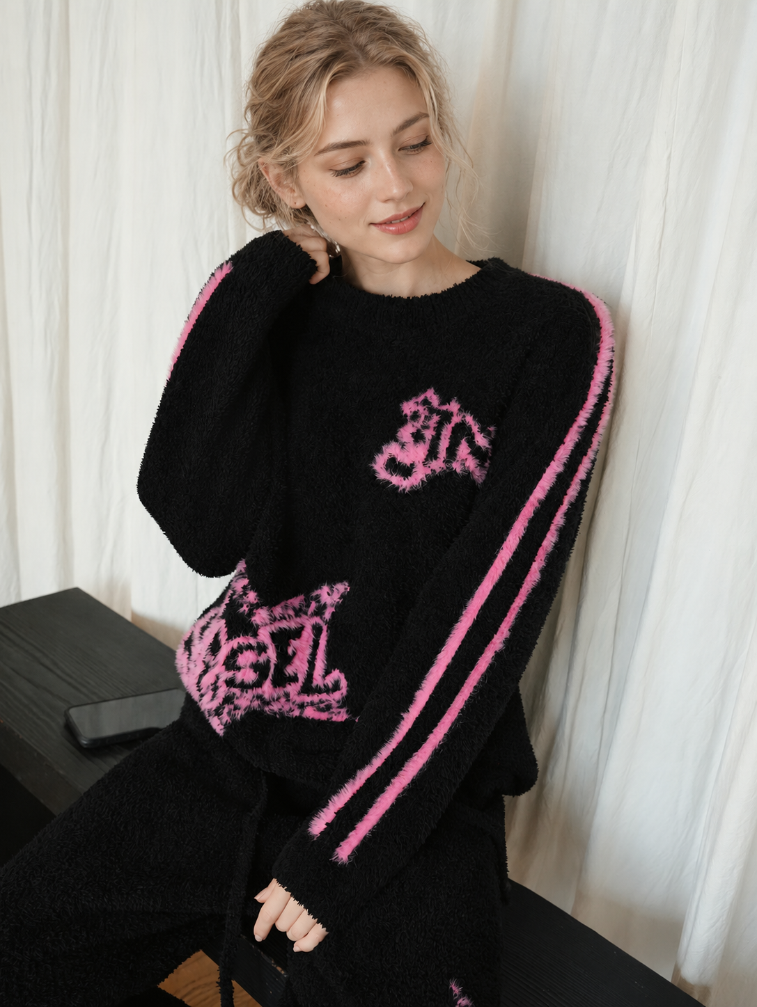 Close view of the pink graffiti lettering and twin sleeve stripes on a black fleece pullover